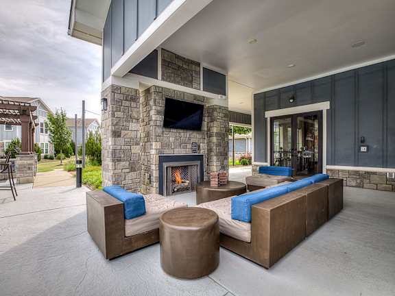 A modern outdoor living space with a stone fireplace and seating area.