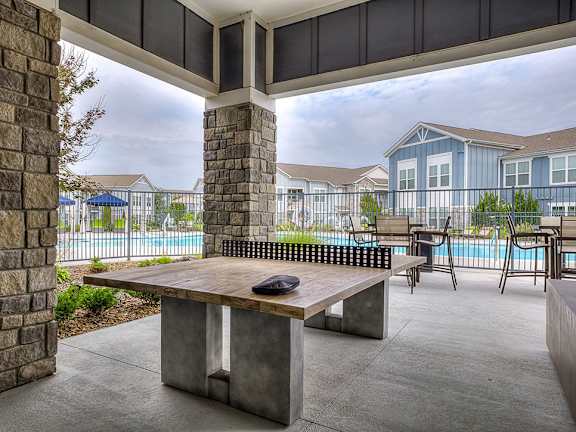 A patio with a table and chairs overlooking a pool.