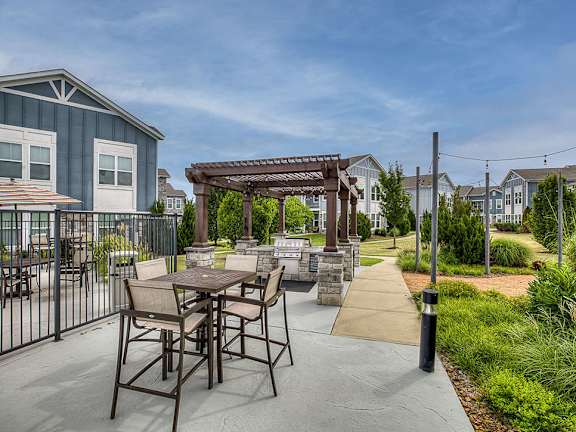 A patio with a table and chairs is surrounded by a fence and houses.