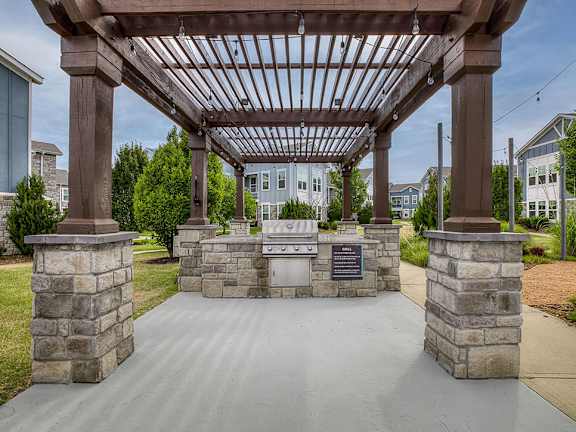 A wooden pergola with a signboard is in the foreground with a residential area in the background.