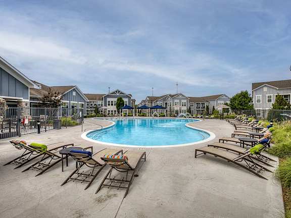 A large swimming pool surrounded by lounge chairs in a residential area.