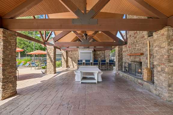 A patio with a white table and chairs under a wooden roof.