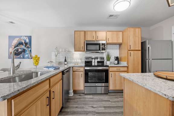 A kitchen with wooden cabinets and a marble countertop.