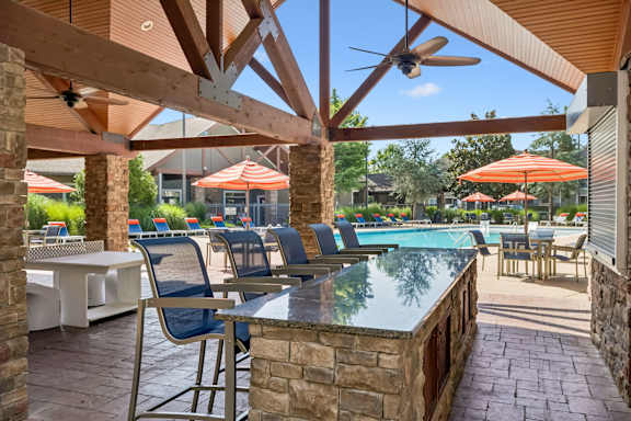 A patio with a table and chairs overlooking a pool.