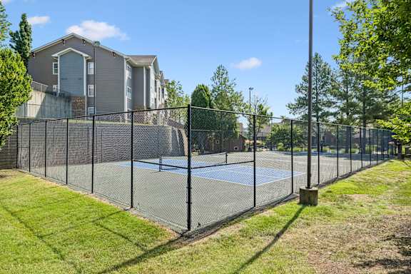 A tennis court is enclosed by a black fence.