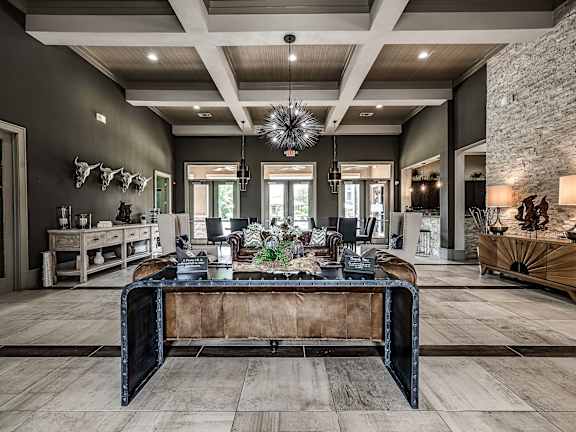 A large, modern living room with a dark brown leather sofa and a stone wall.