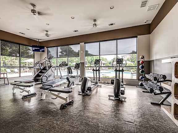 A gym with a variety of equipment including treadmills, weights, and exercise machines.