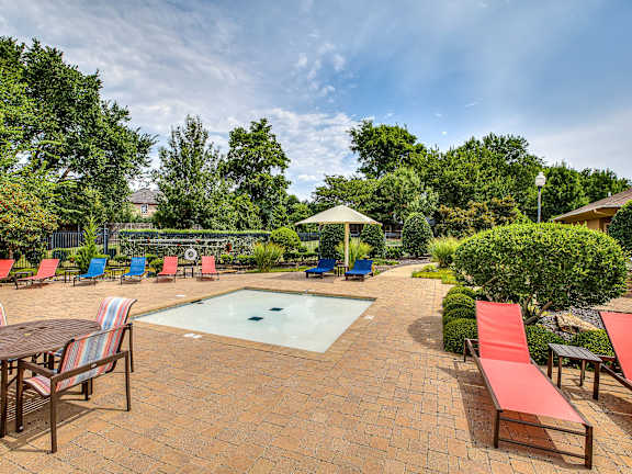 A pool surrounded by red lounge chairs and a table.