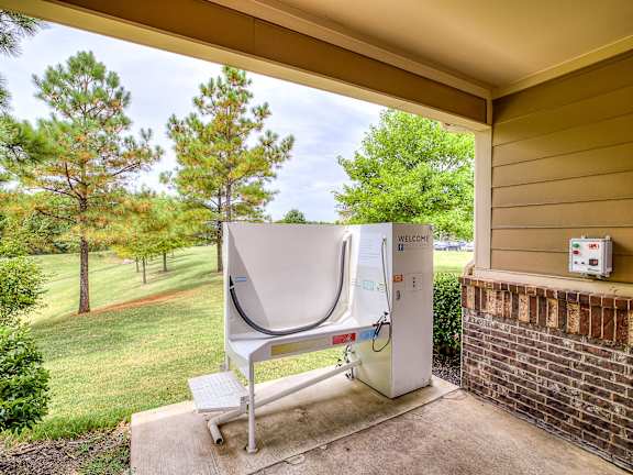 A portable toilet is placed on a concrete slab on a covered porch.