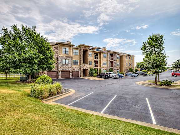A large apartment complex with a parking lot in front.