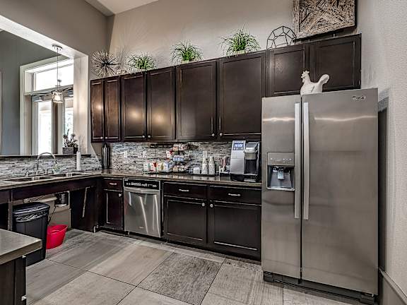 A modern kitchen with dark brown cabinets and stainless steel appliances.