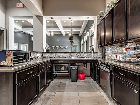 A kitchen with dark wood cabinets and a stone backsplash.
