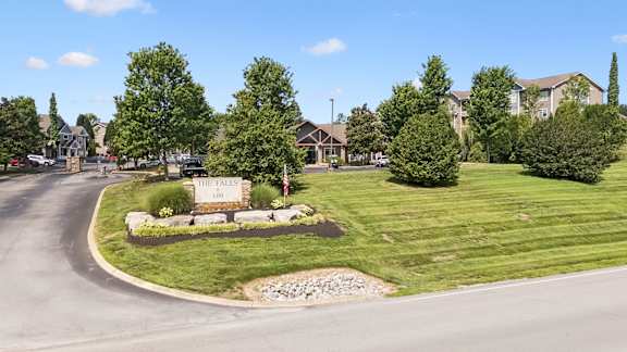 A sign that says "The Pines" is in front of a grassy area.
