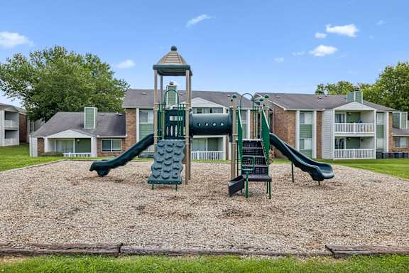 A playground with a green slide and a wooden structure.