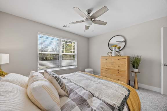 A bedroom with a bed, dresser, and window.
