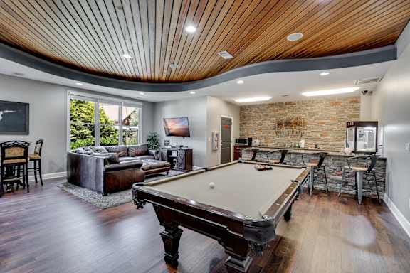 A pool table is in the middle of a room with a brick wall.