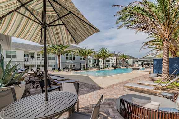 Table & Chairs With Umbrella At The Pool Sundeck