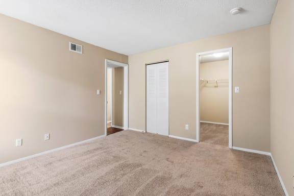 Carpeted Bedroom With Attached Walk-In Closet
