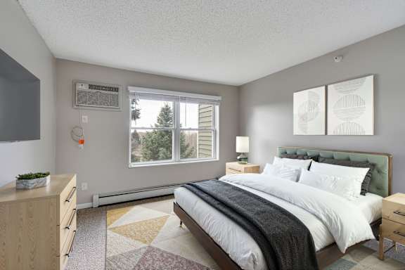 A bedroom with a large bed and a window with a wooded view.