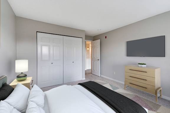 A bedroom with a large bed, a dresser, and a large closet.