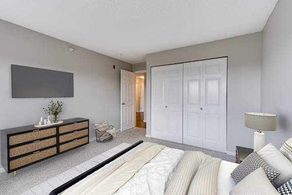 A large bedroom with a bed, dresser, and large closet.