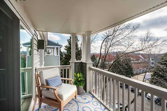 A balcony with a chair and a view of the neighborhood.