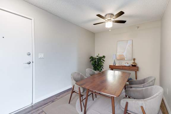 A dining area with a wooden table, a ceiling fan, and grey chairs.