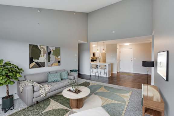 A large living room with a vaulted ceiling, a grey couch and a coffee table.