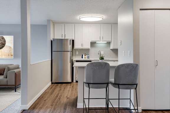 A virtually staged kitchen with stainless steel appliances, a white countertop, and white cupboards.