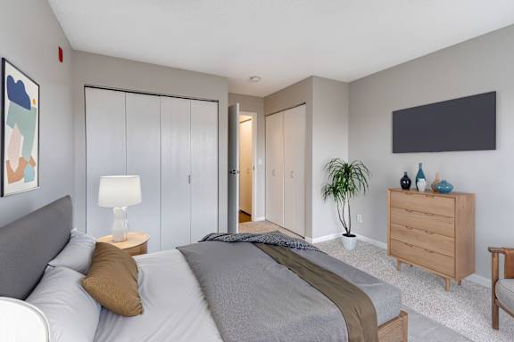 A bedroom with a bed, nightstand, and two closets.