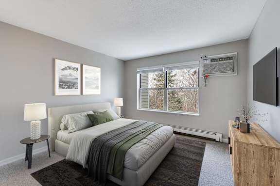 A bedroom with a large bed and window with a wooded view.