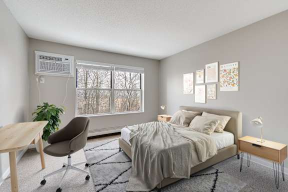 A bedroom with a bed, chair, and window with a wooded view.