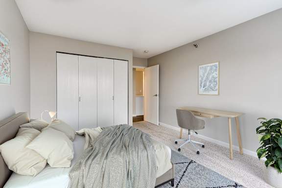 A bedroom with a bed, a desk, and a chair.