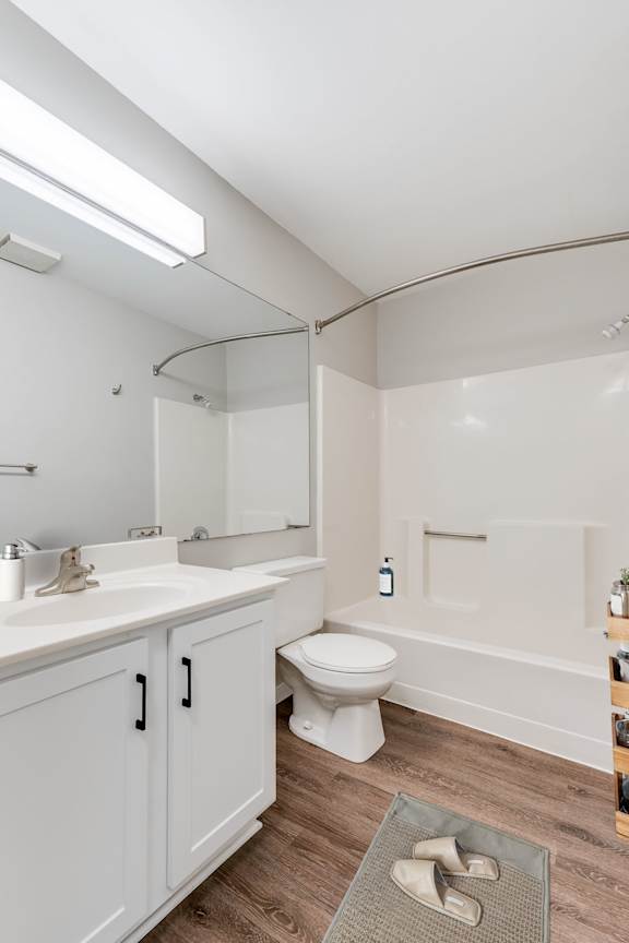 A large bathroom with a tall ceiling, a bathtub, and a safety grab bar in the bathtub.