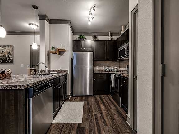 A kitchen with a stainless steel refrigerator and wooden floors.