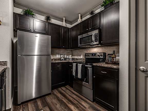 A kitchen with dark wood cabinets and a stainless steel refrigerator.