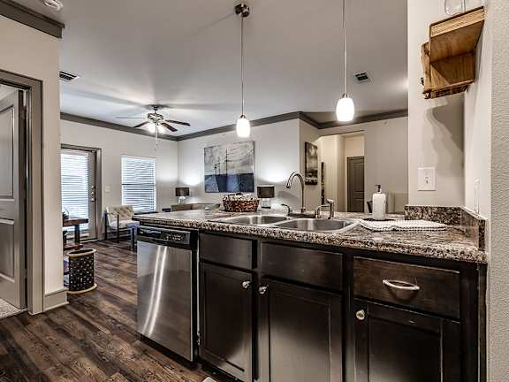 A modern kitchen with dark wood floors and stainless steel appliances.