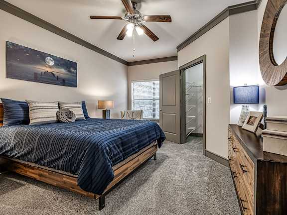 A bedroom with a bed, dresser, and ceiling fan.