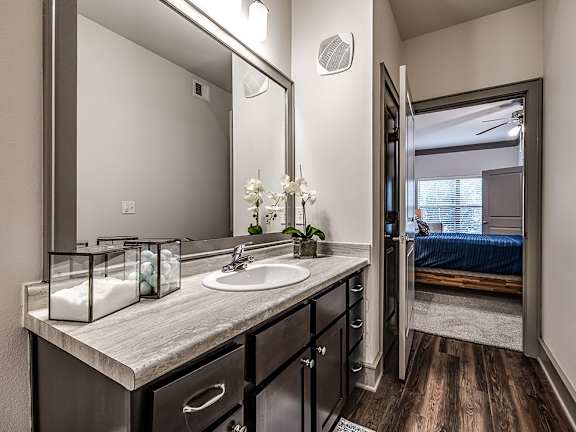 A bathroom with a sink, mirror, and wooden floors.