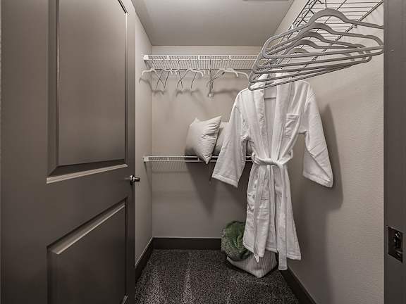 A white robe is hanging on a rack in a small room.