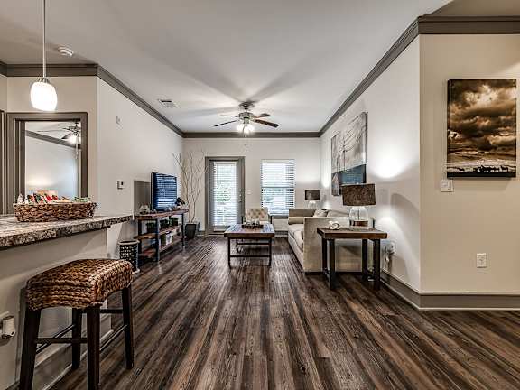 A living room with a dark wood floor and a ceiling fan.