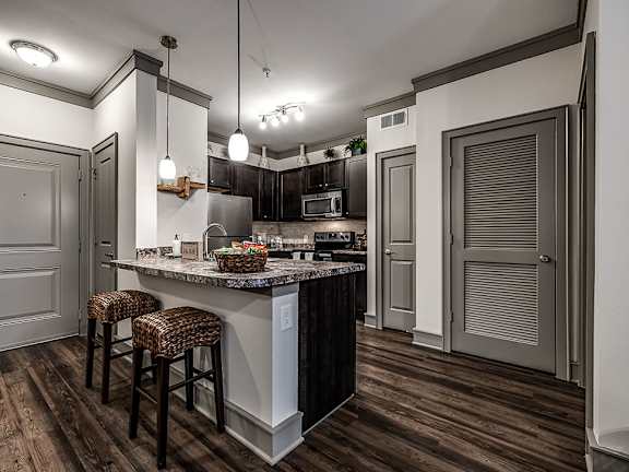A kitchen with a bar area and a counter with a bowl of fruit on it.