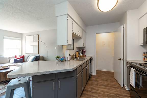 A kitchen with a white countertop and grey cabinets.