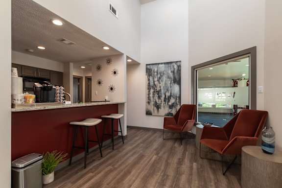 A modern bar area with a red wall and wooden floors.