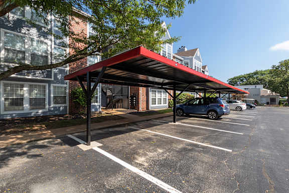 A parking lot with a red canopy and cars parked underneath.