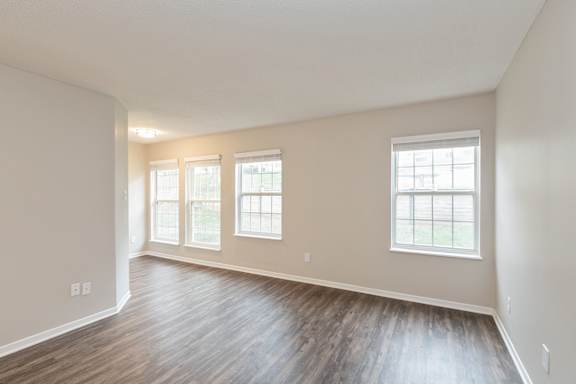 A room with wooden floors and three windows.