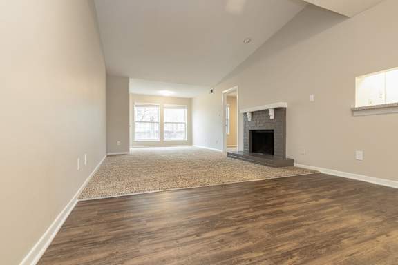 A living room with a fireplace and a rug on the floor.