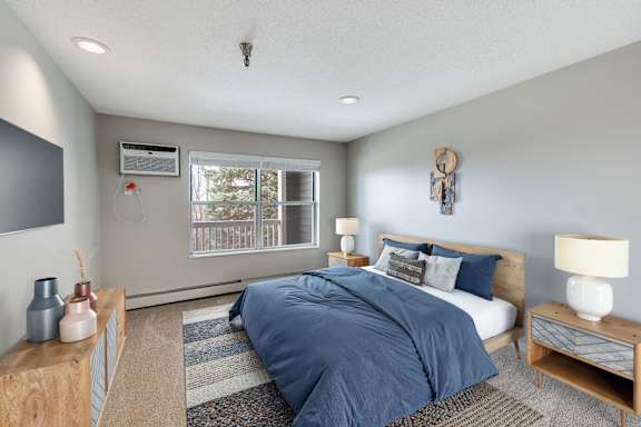 A bedroom with a bed, nightstands, and a window.