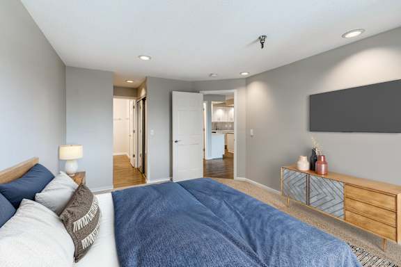A bedroom with a large bed and a view into the rest of the apartment.