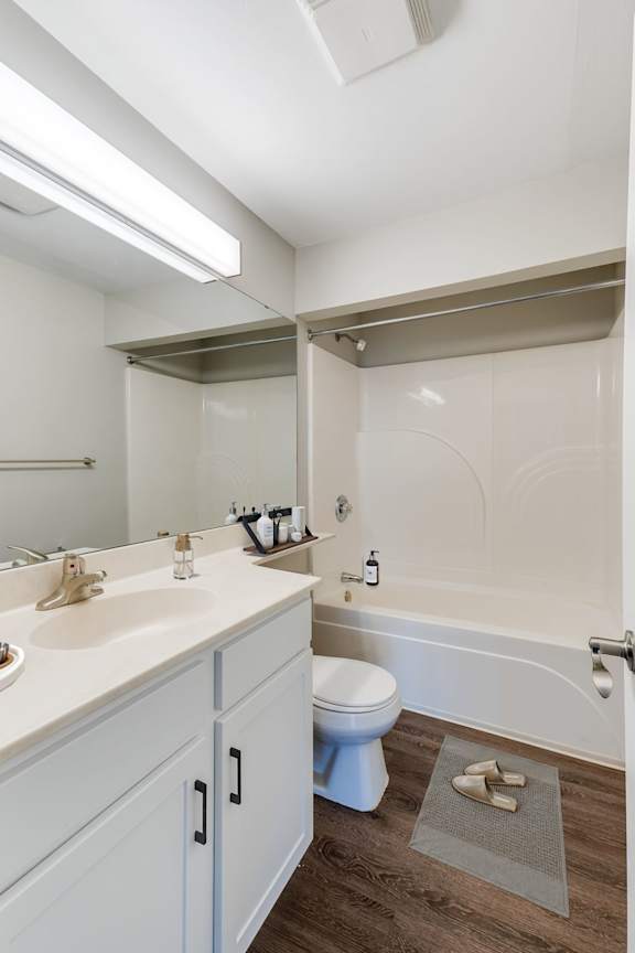 A spacious white bathroom with a bathtub, a sink with space for personal items, and a towel rack.